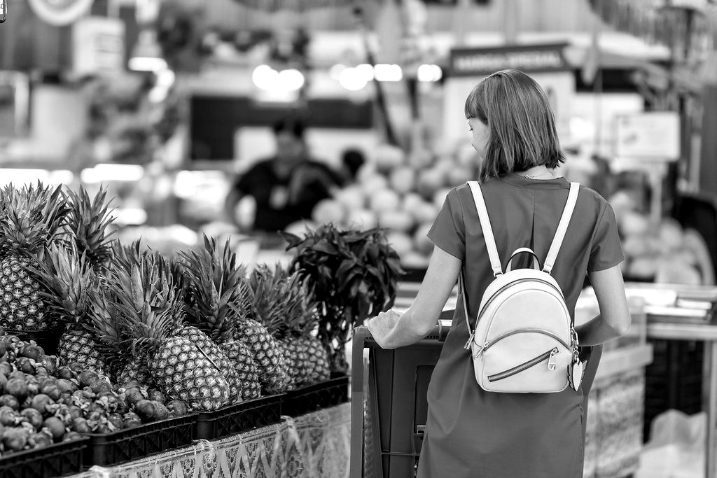 A shopper with a trolley beside pineapples in a supermarket