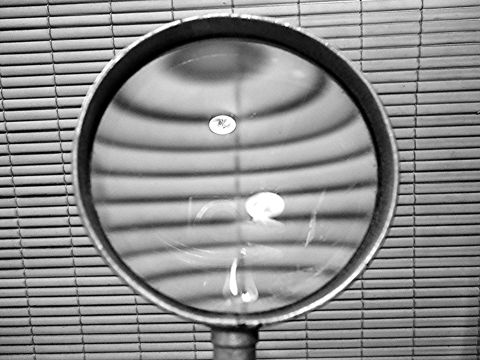 A magnifying glass held in front of a metal grille