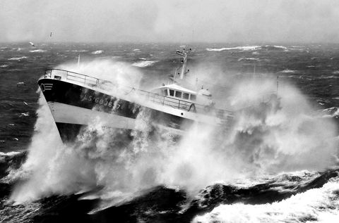 A fishing trawler ploughing through heavy waves in a storm