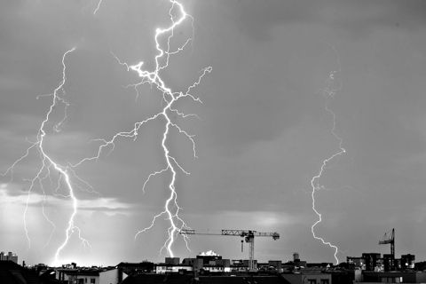Several lightning bolts striking over a city skyline at dusk