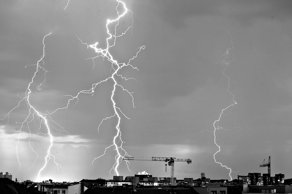 Several lightning bolts striking over a city skyline at dusk