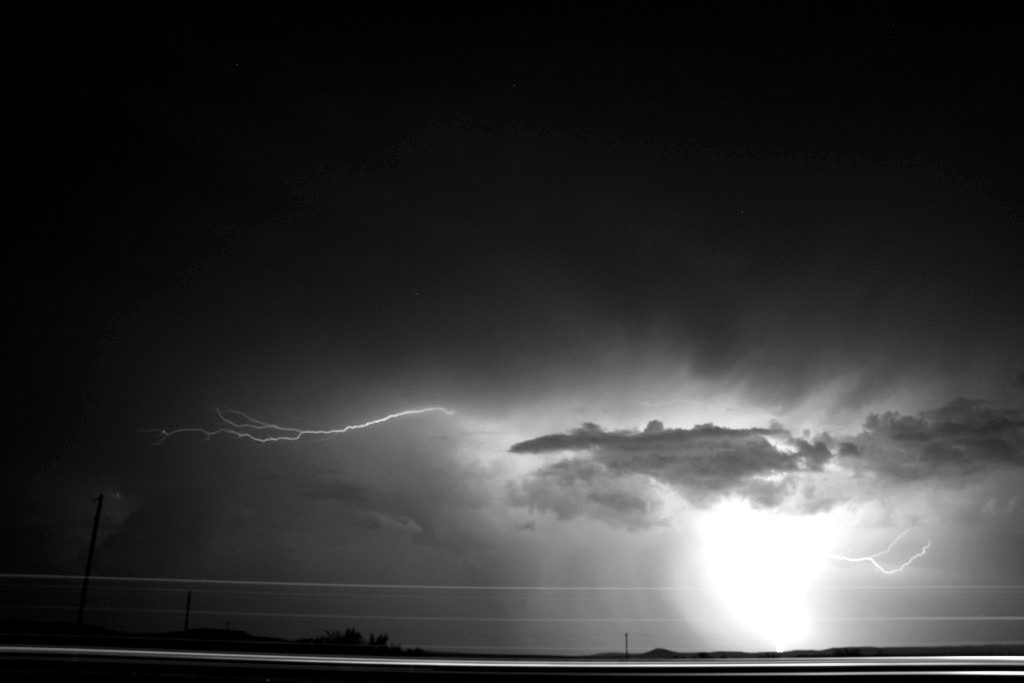 Distant lightning beneath a storm cloud at night