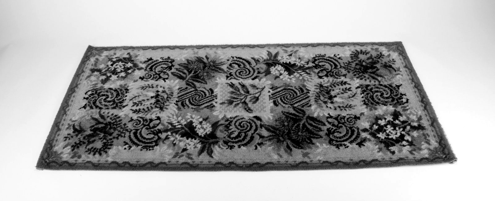 A floral embroidered rug laid flat on a white surface