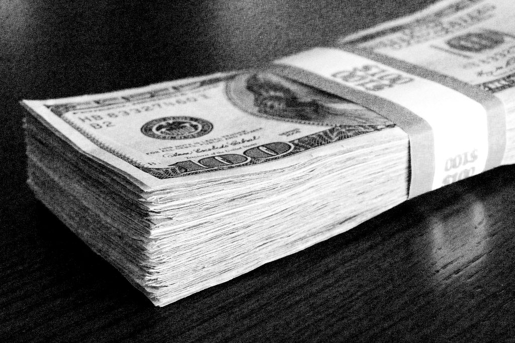 A stack of US hundred-dollar bills on a dark table