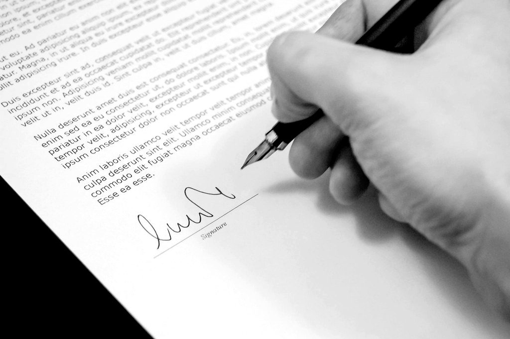 A hand signing a document with a fountain pen