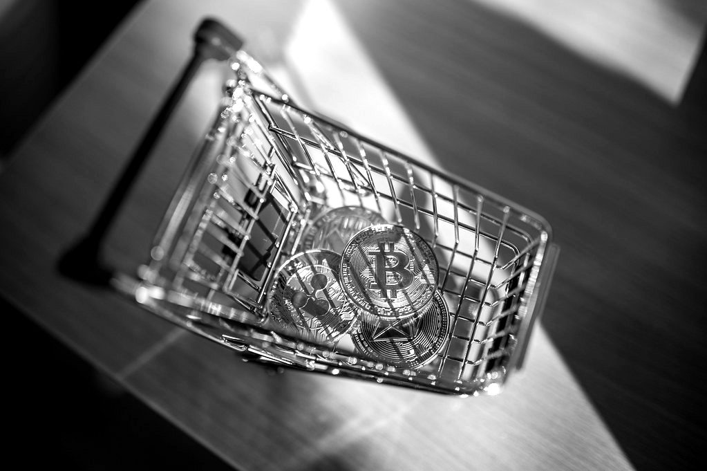 A gold-coloured Bitcoin token inside a miniature shopping trolley