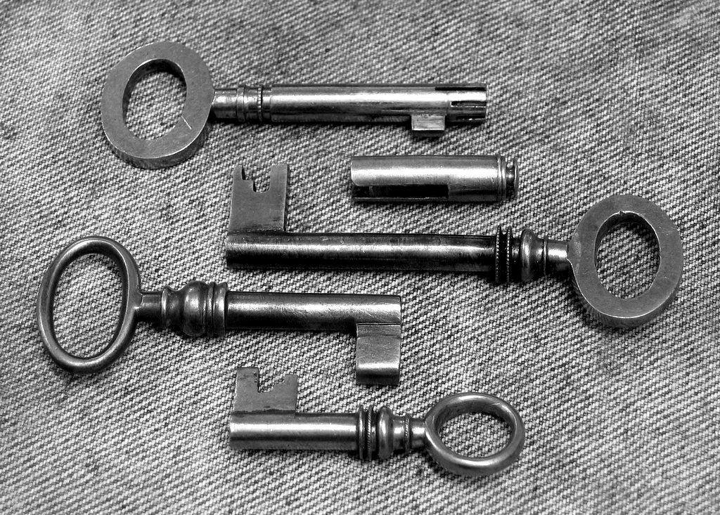 Several antique keys laid out on denim