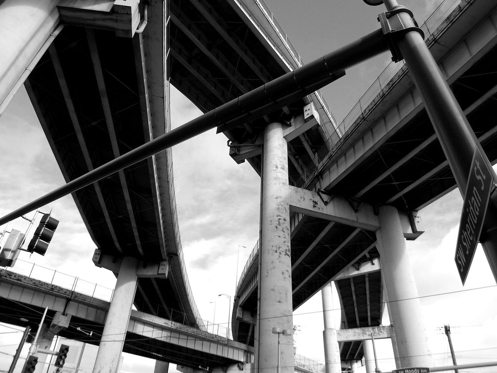 Curving concrete highway overpasses stacked above a street, seen from below