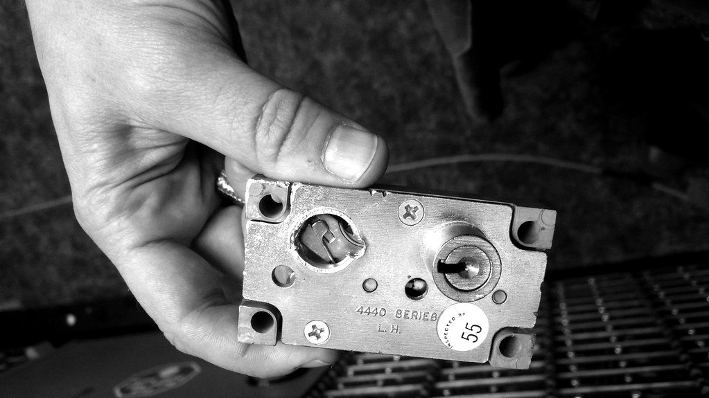 A hand holding the lock mechanism of a safe deposit box