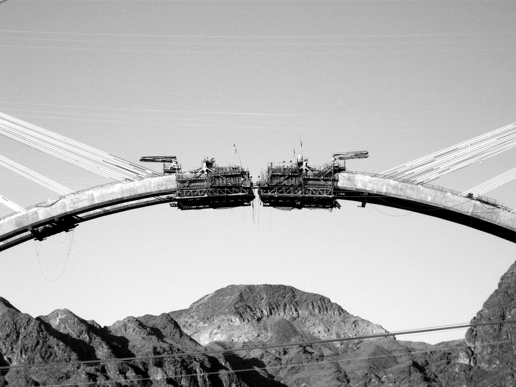 The two halves of an arch bridge meeting during construction over a canyon
