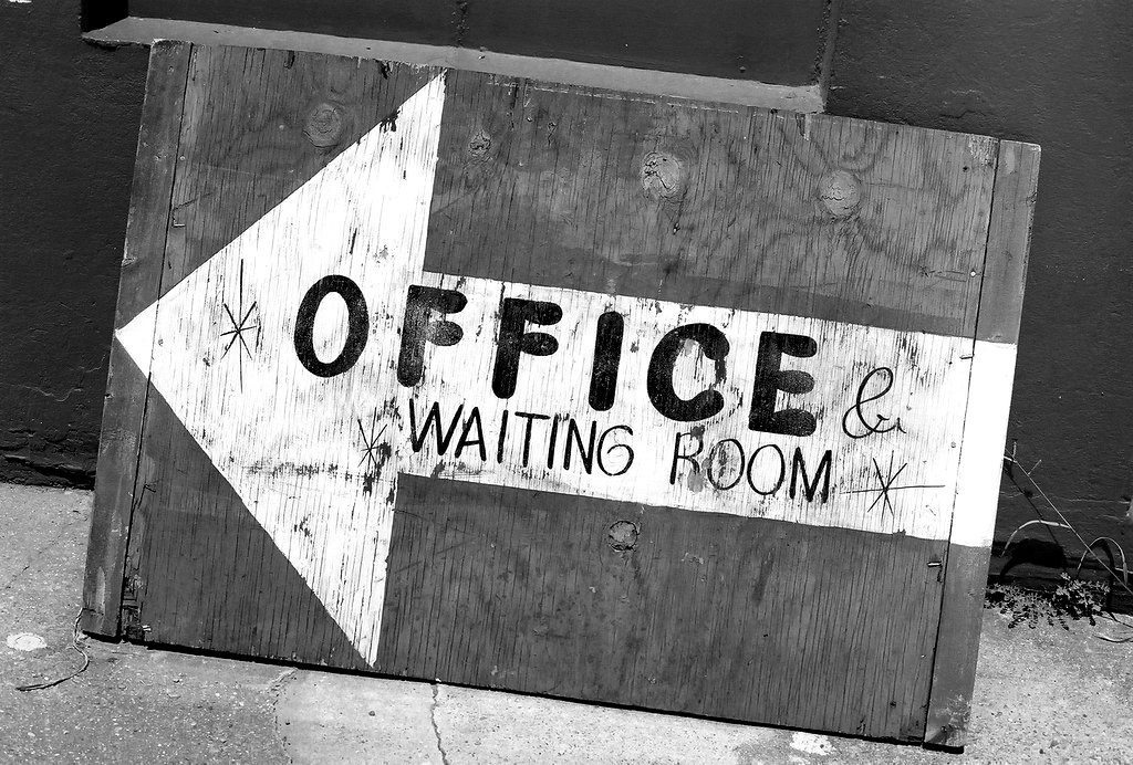 A hand-painted 'Office & waiting room' arrow sign